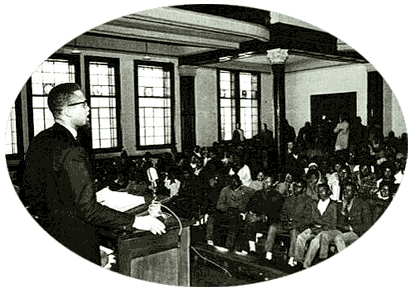 Black & White Photograph showing Malcolm X addressing an indoor meeting of Afro-Americans in the early 1960's.